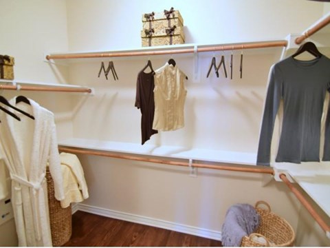 a walk in closet with clothes hanging on the wall