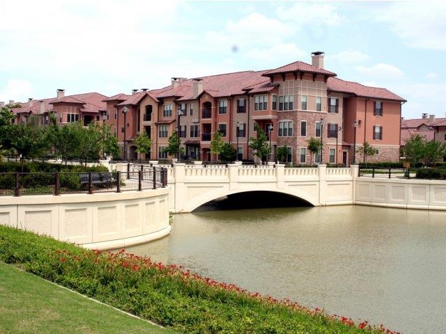 a bridge over a river in front of some apartments