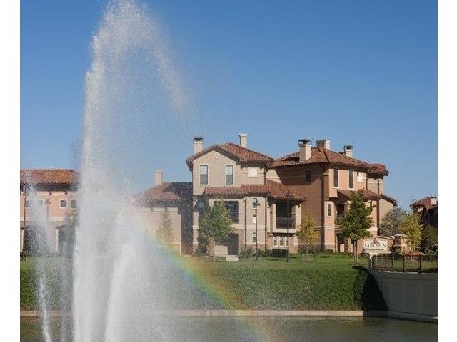 a water fountain with a rainbow in front of a house
