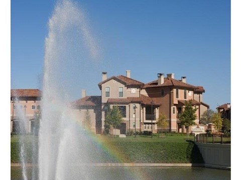 a water fountain with a rainbow in front of a house