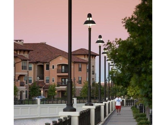 a woman walking down a sidewalk next to street lamps