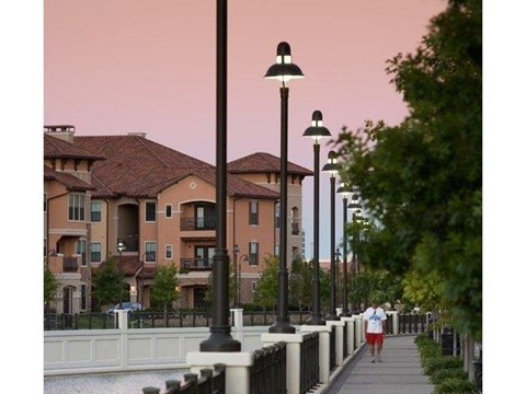 a woman walking down a sidewalk next to street lamps