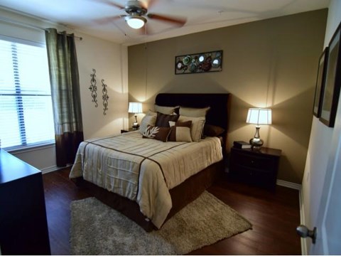 A bedroom with a bed, two lamps, and a ceiling fan.