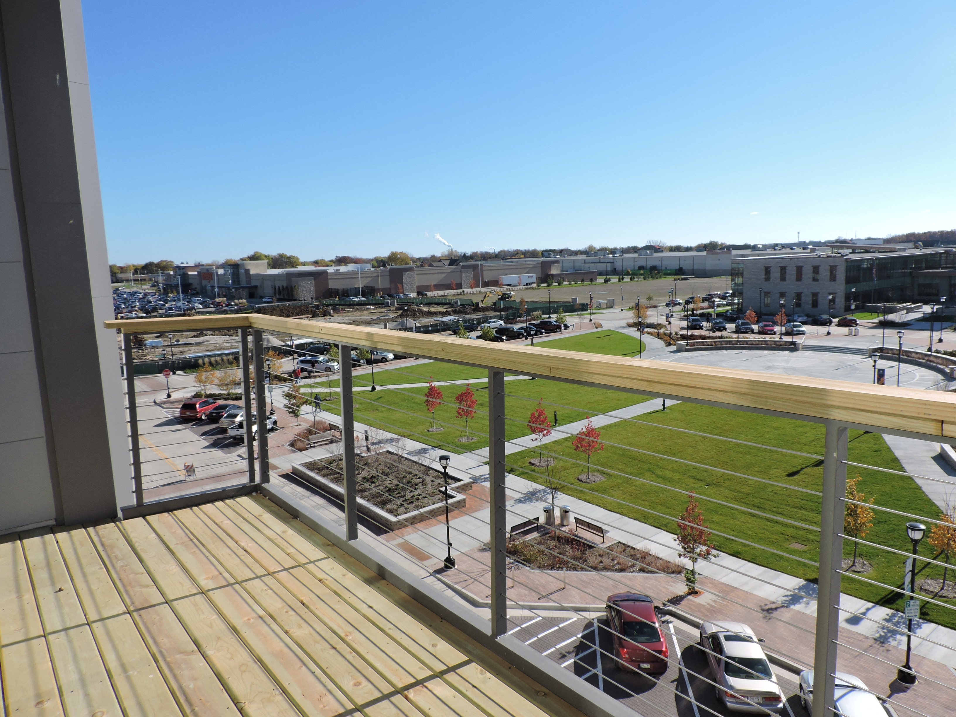 a balcony with a view of a park and a parking lot