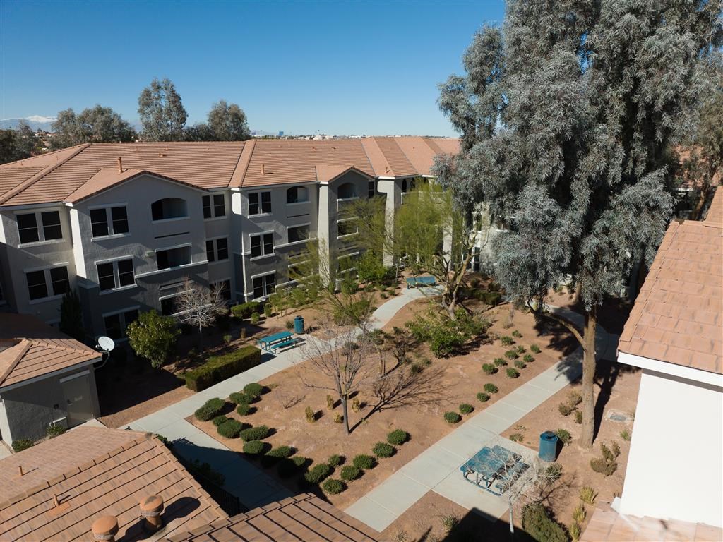 an aerial view of an apartment complex with a pool and trees