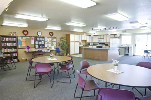 a room with tables and chairs and a kitchen