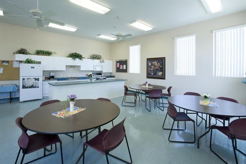 a multipurpose room with tables and chairs and a kitchen