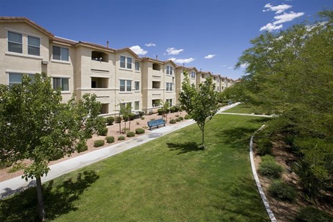a row of apartment buildings with green grass and trees