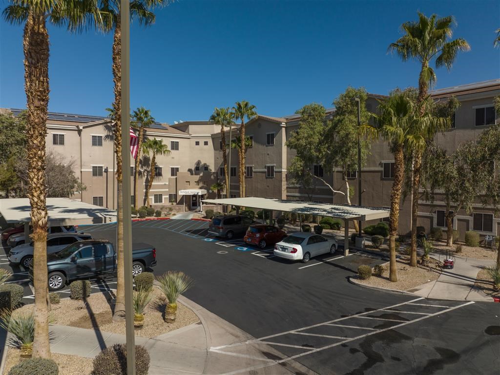 a parking lot with cars and palm trees in front of a building