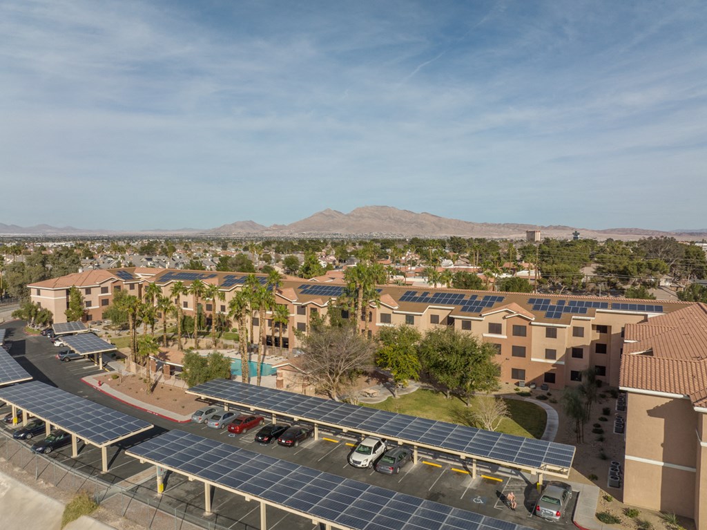 an aerial view of an apartment complex with solar panels in the parking lot