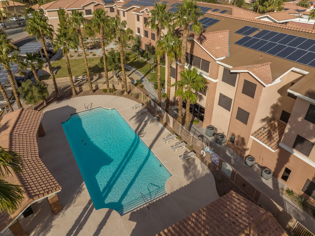 an aerial view of a swimming pool and a building with solar panels
