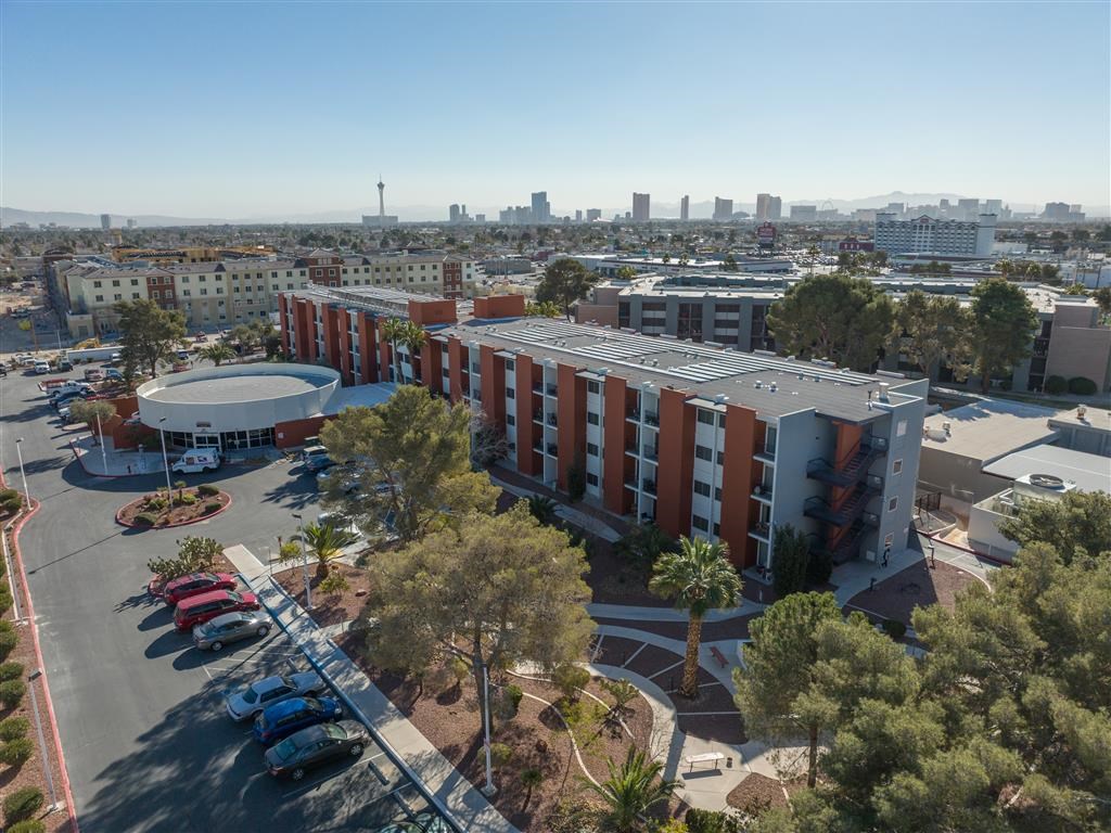 an aerial view of a building and parking lot with a city in the background