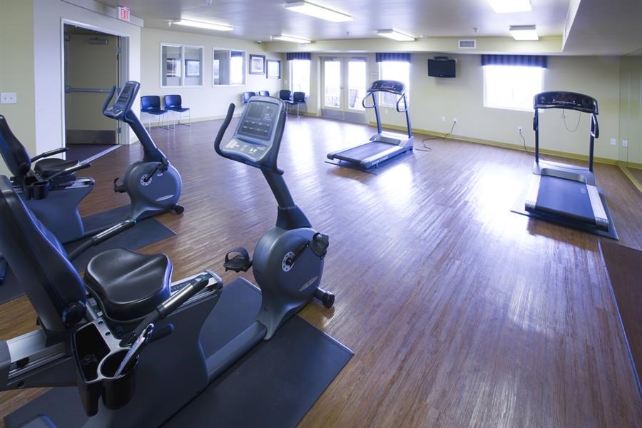 a gym with various exercise equipment on a wooden floor