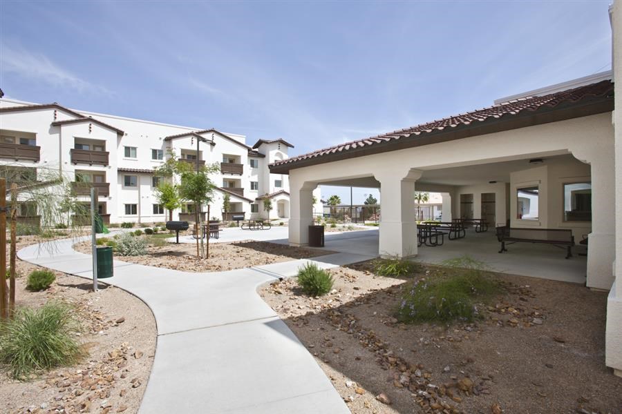 a courtyard with tables and benches in front of an apartment building