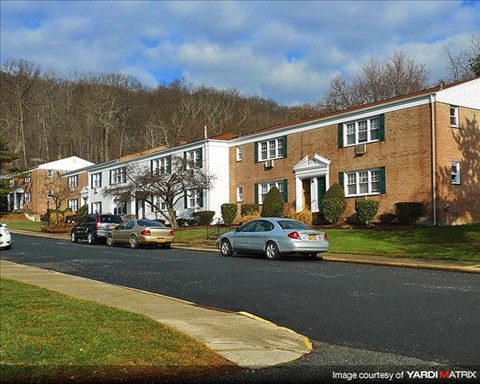 A street view of a residential area with cars parked on the side of the road.