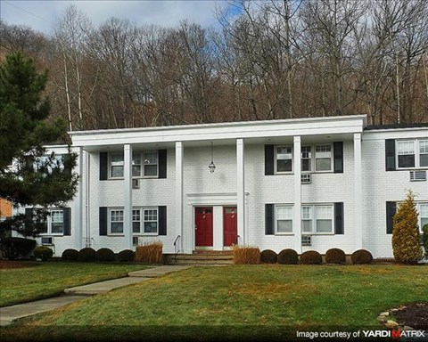 A white two story house with a red door and windows.