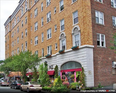A red brick building with a white awning and a tree in front of it.