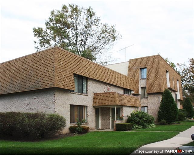 A house with a brown roof and a green lawn in front.