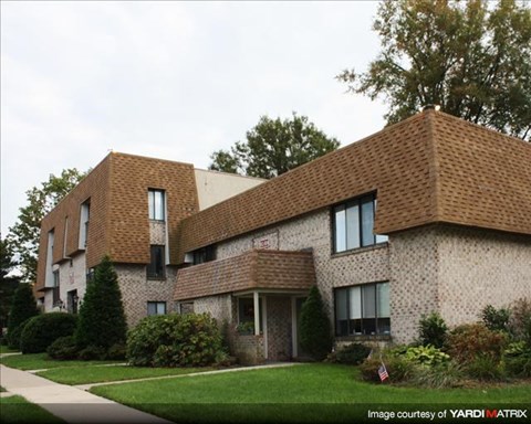 A modern house with a brown roof and a well-maintained lawn.