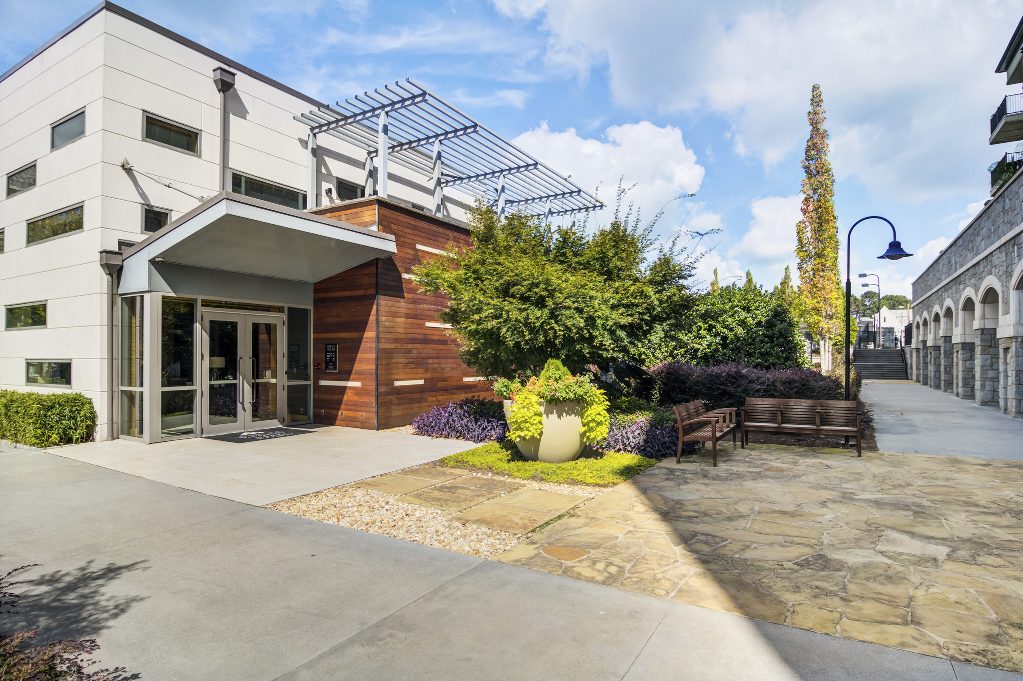 the entrance to a building with a stone sidewalk and a bench