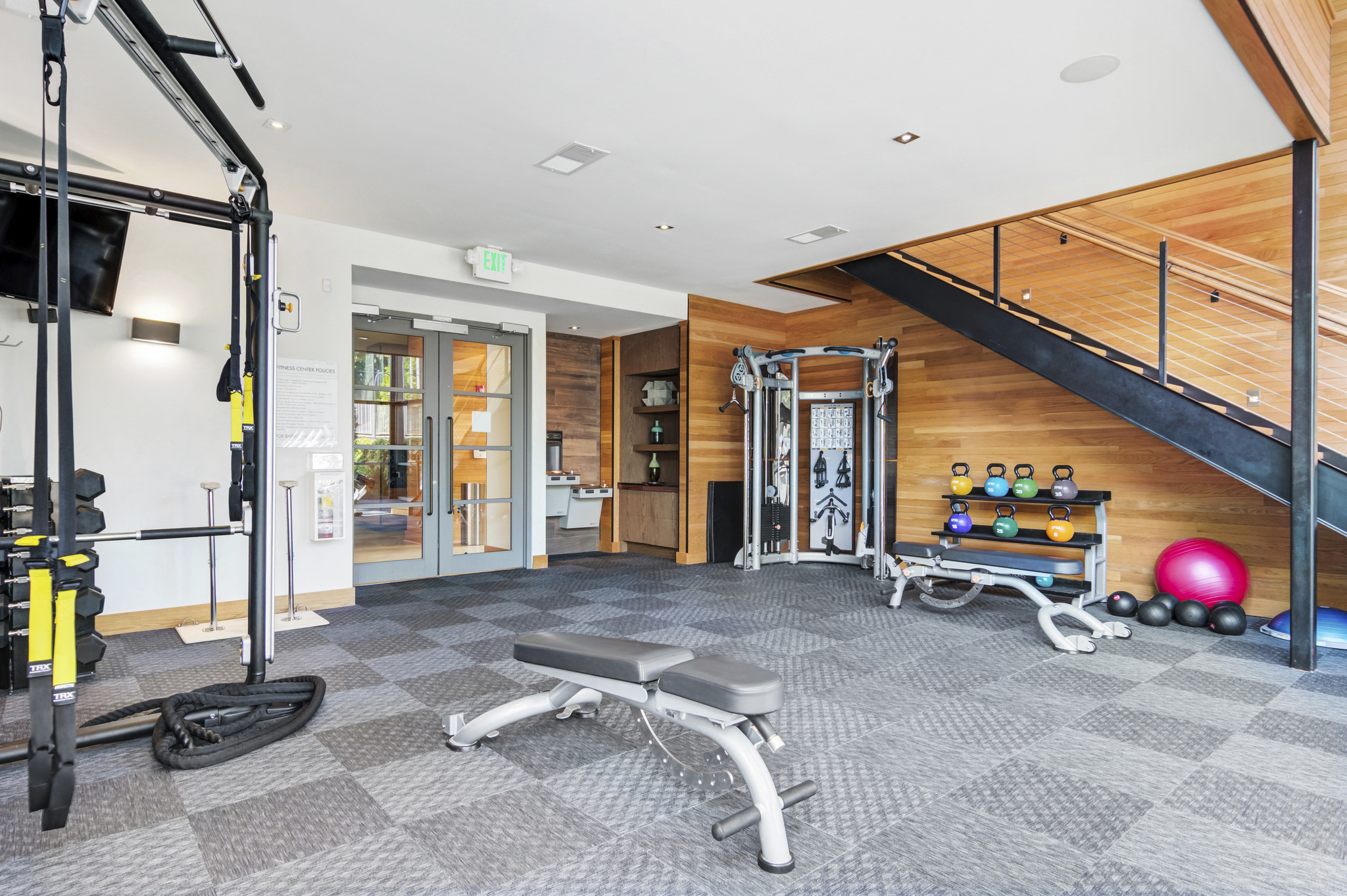 a gym with weights and weights on the floor and a staircase