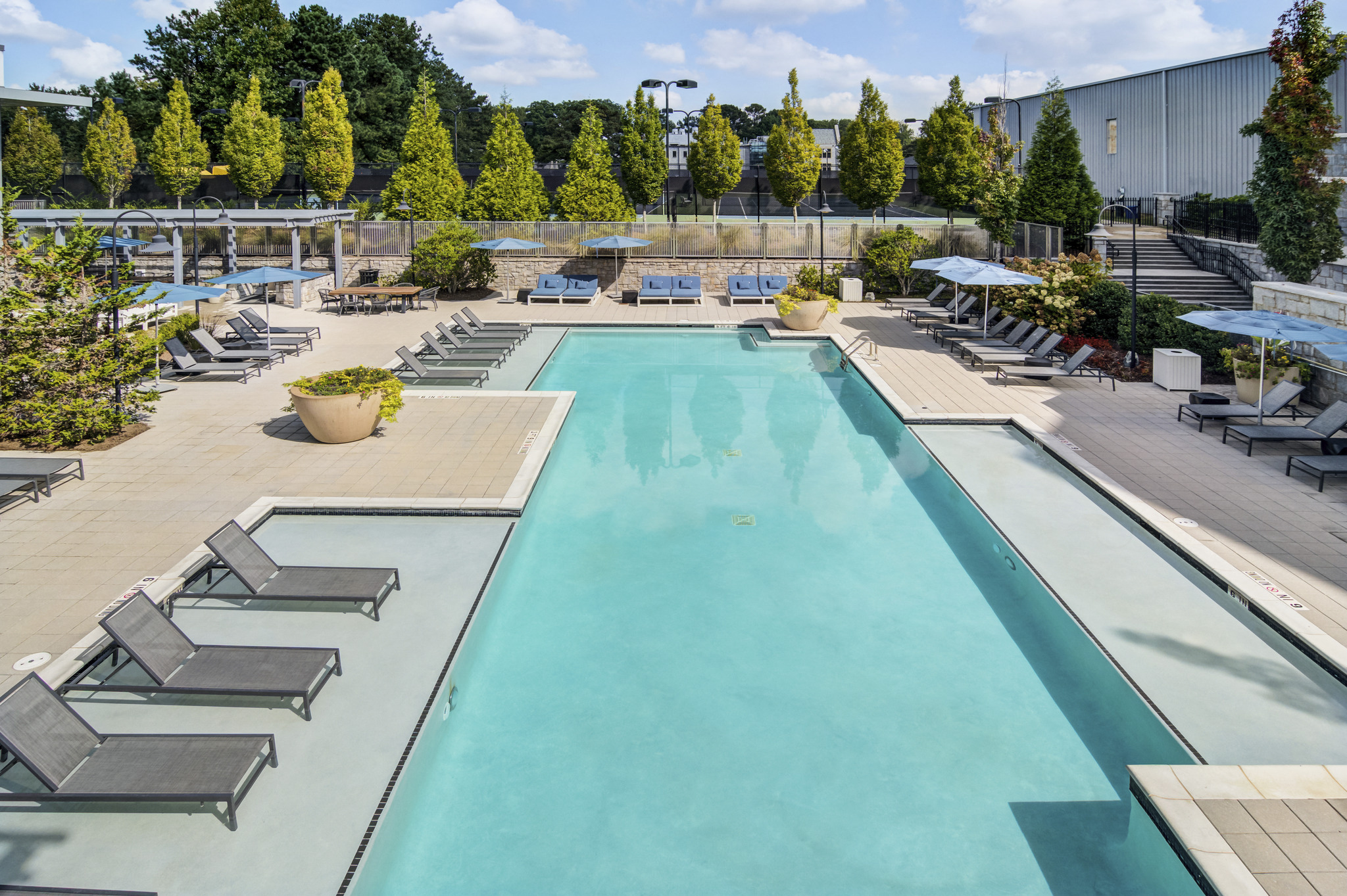 a swimming pool with lounge chairs and trees in the background