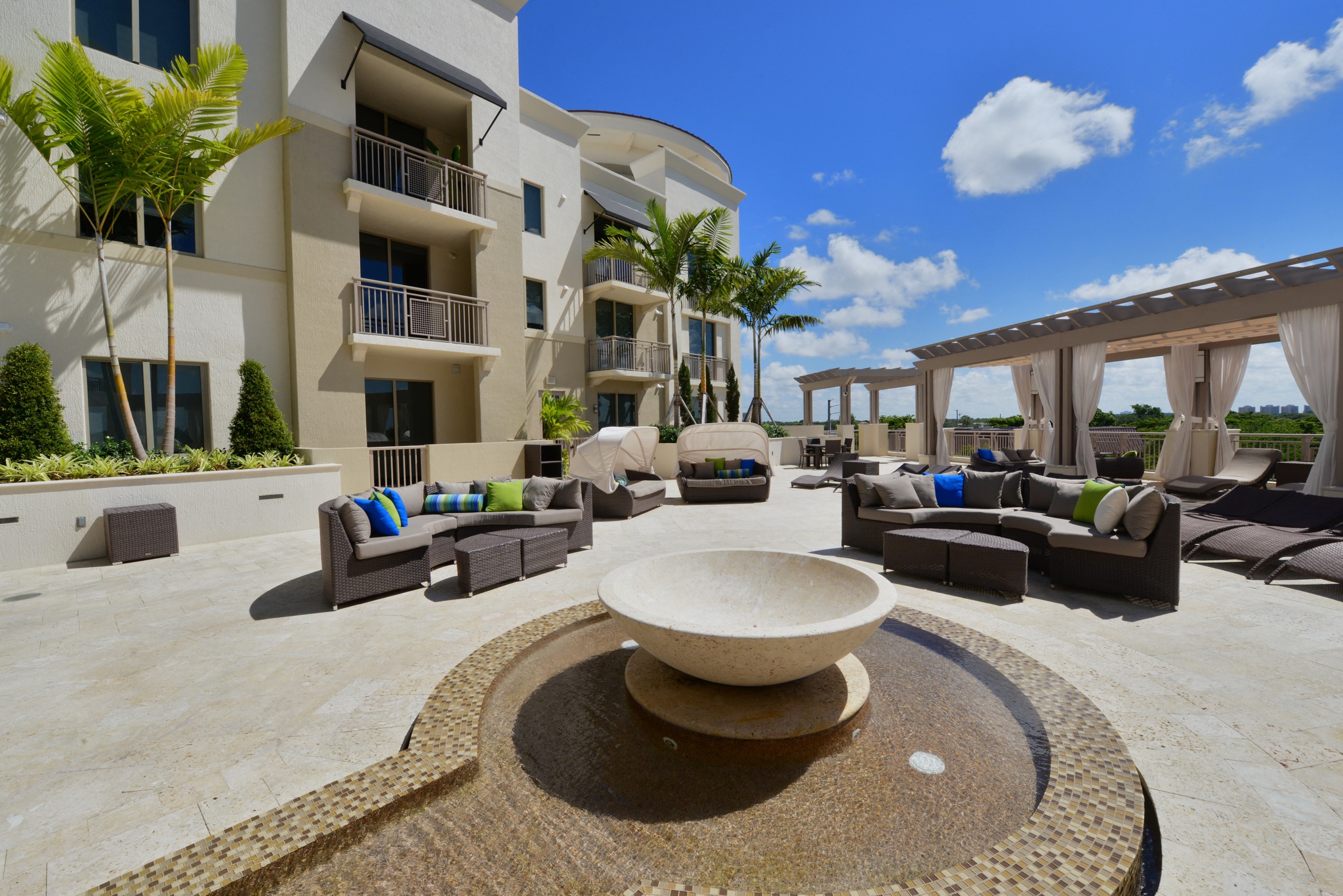 a large patio with couches and chairs and a fountain in front of a building