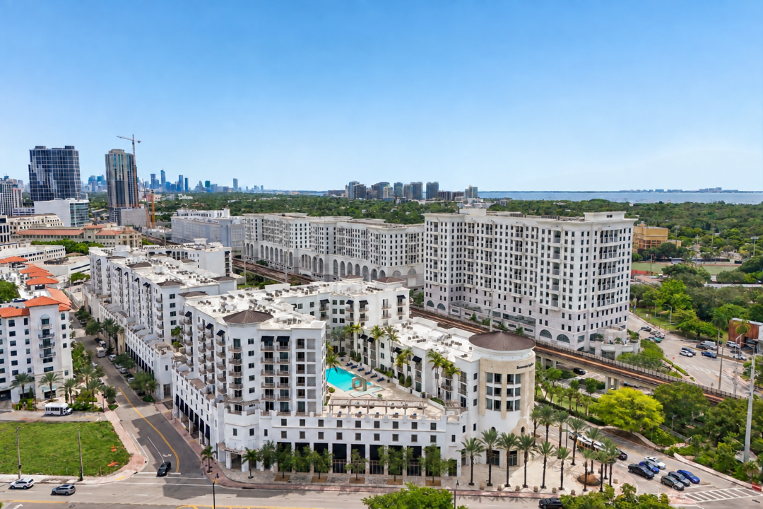 A large white hotel with a pool in the middle of a city.