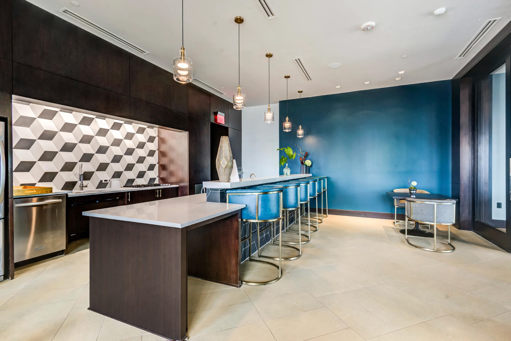 A modern kitchen with a long counter and bar stools.