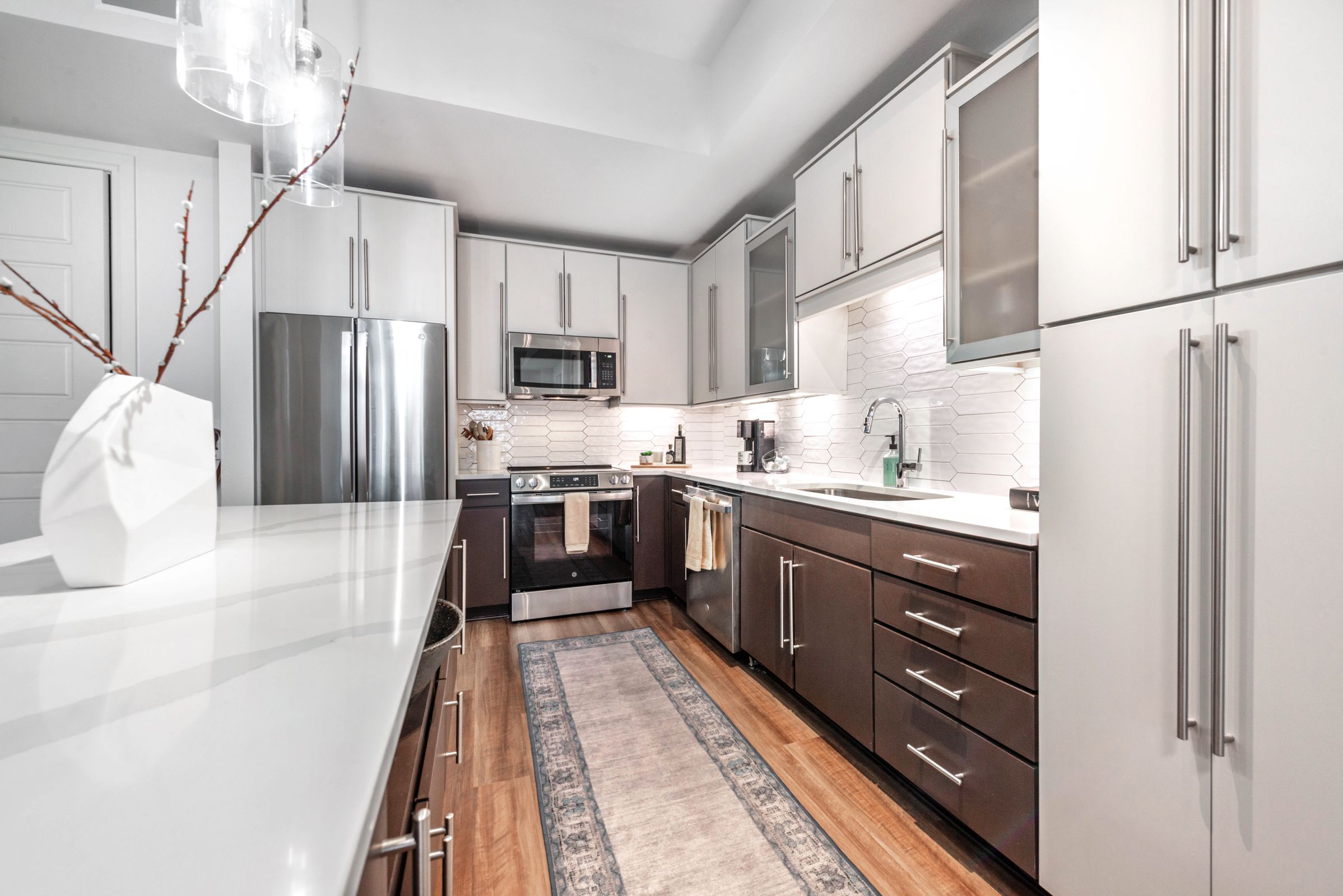 A modern kitchen with white and brown cabinets and a marble backsplash.