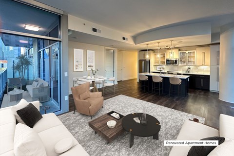 A modern living room with a kitchen in the background.