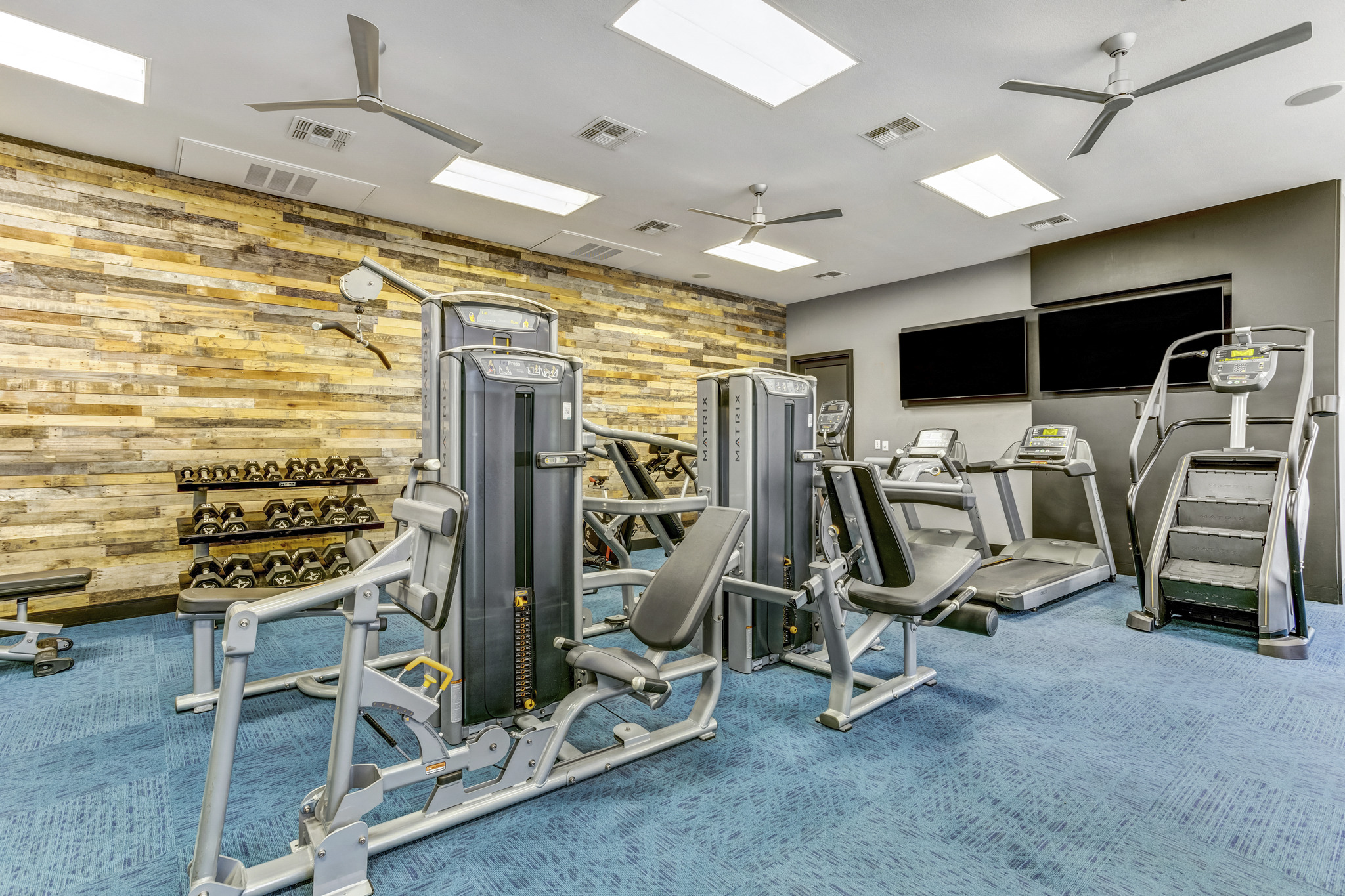 a gym with cardio equipment and a wall of wood paneling