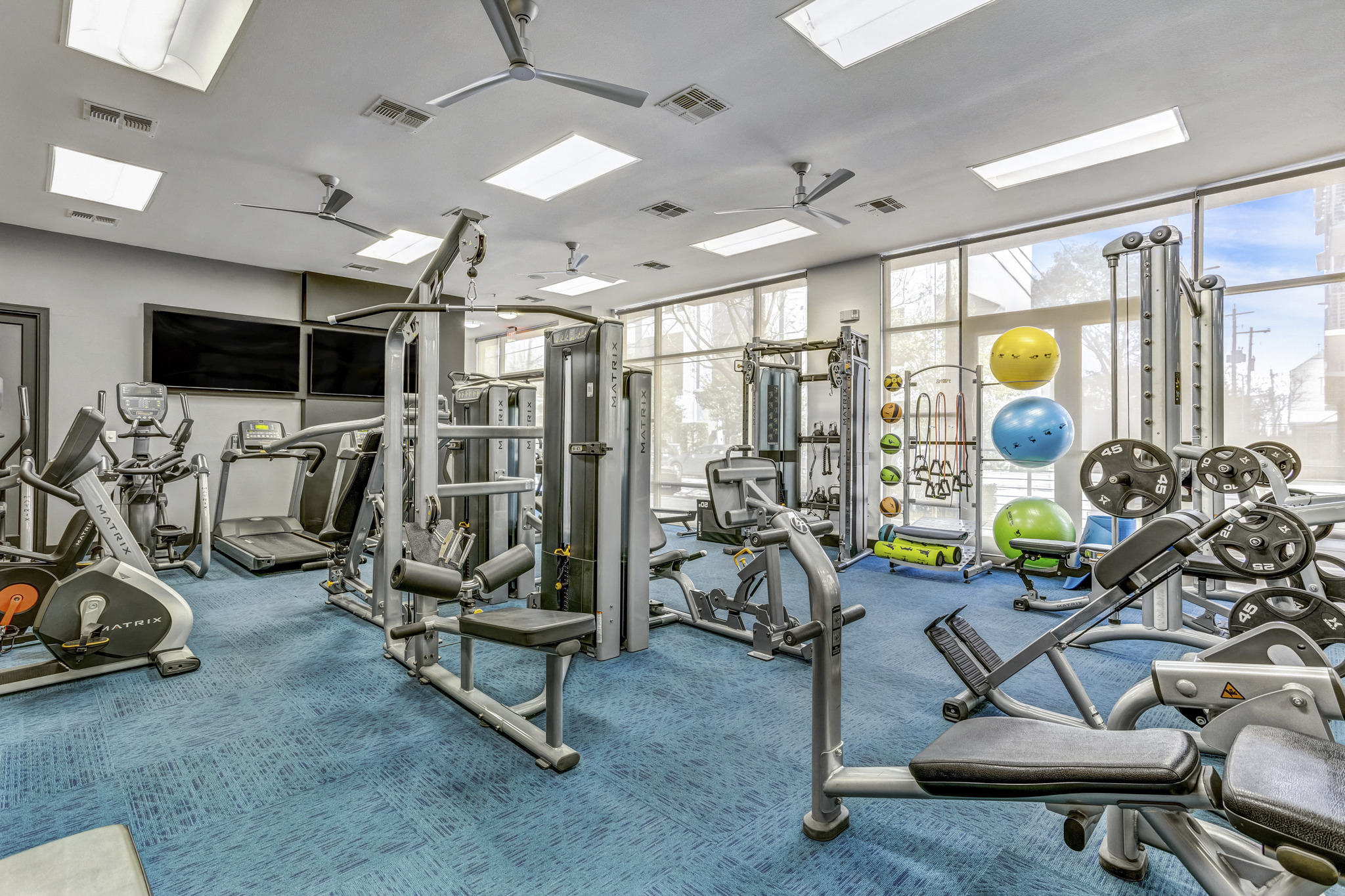 a gym with weights and cardio machines and a window