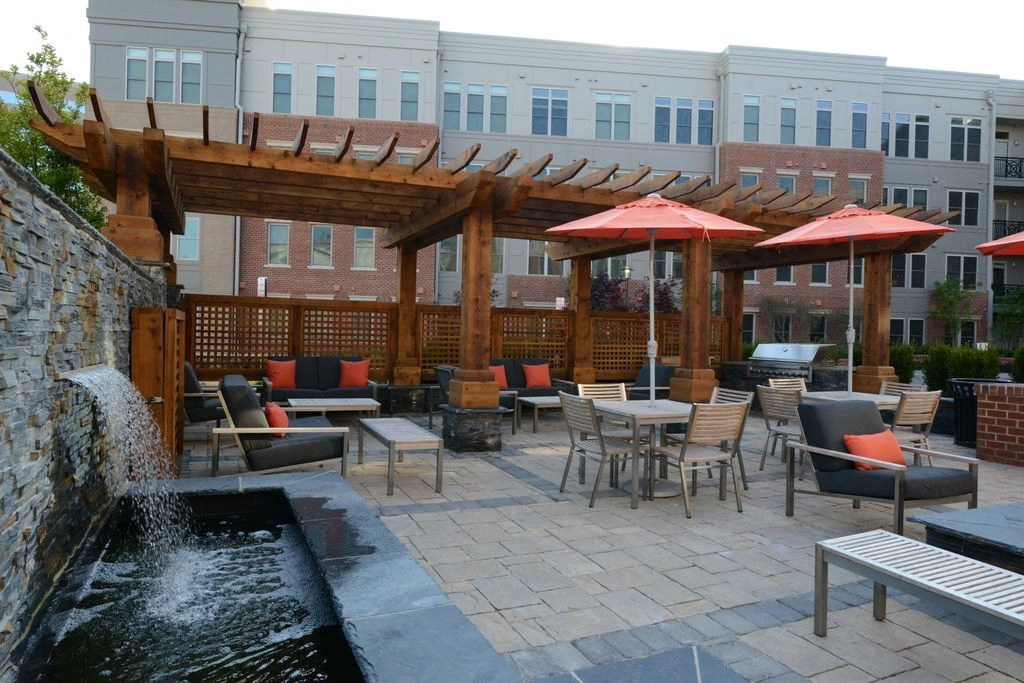 a patio with tables and umbrellas and a water fountain