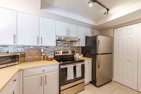 A kitchen with white cabinets and a black fridge.