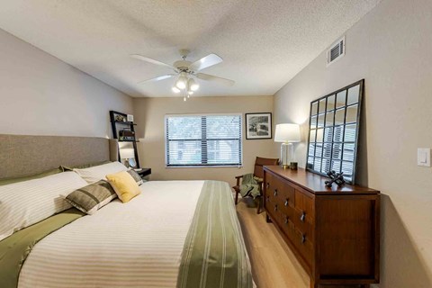 A bedroom with a bed, dresser, and window with blinds.