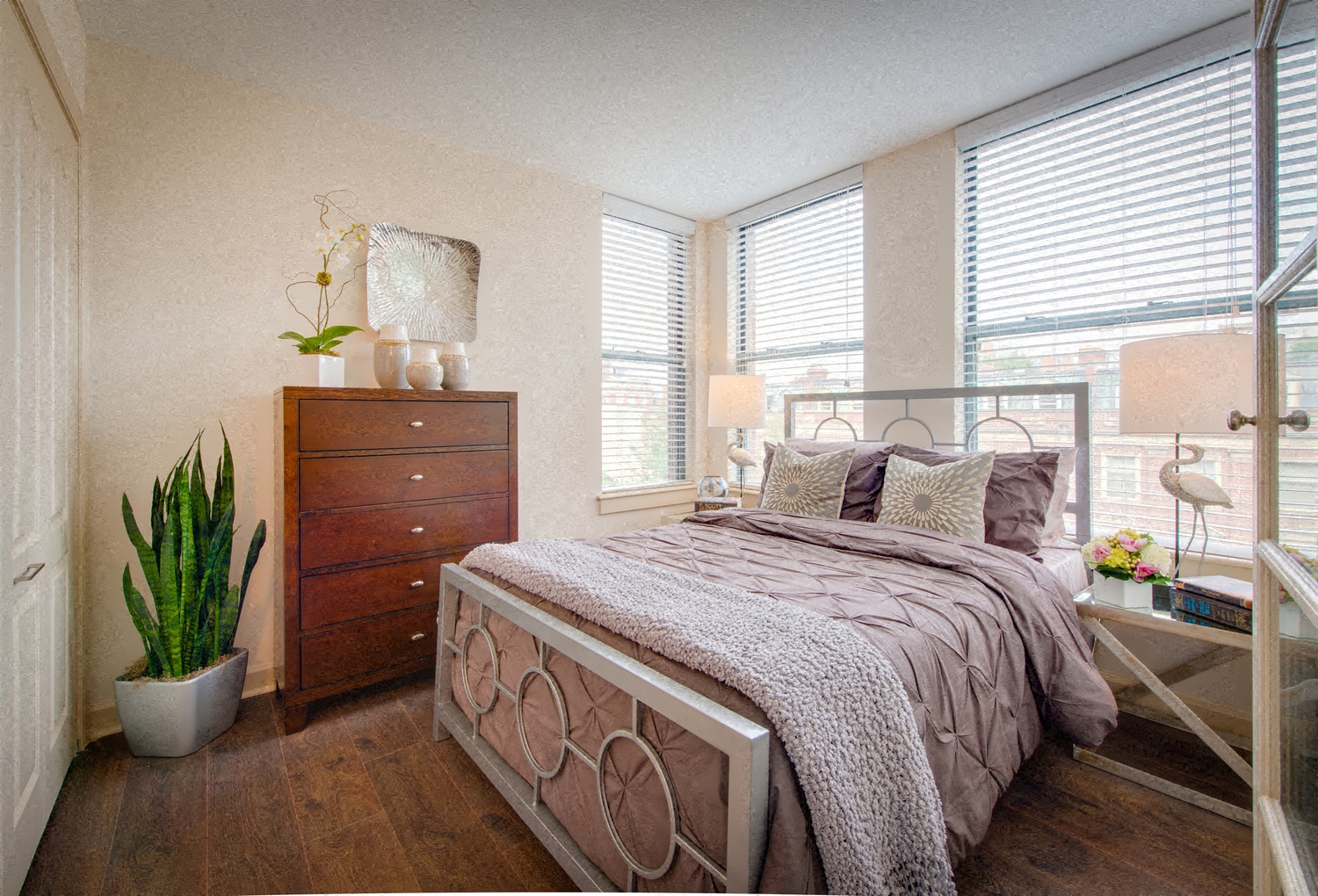 a bedroom with a bed and a dresser and windows
