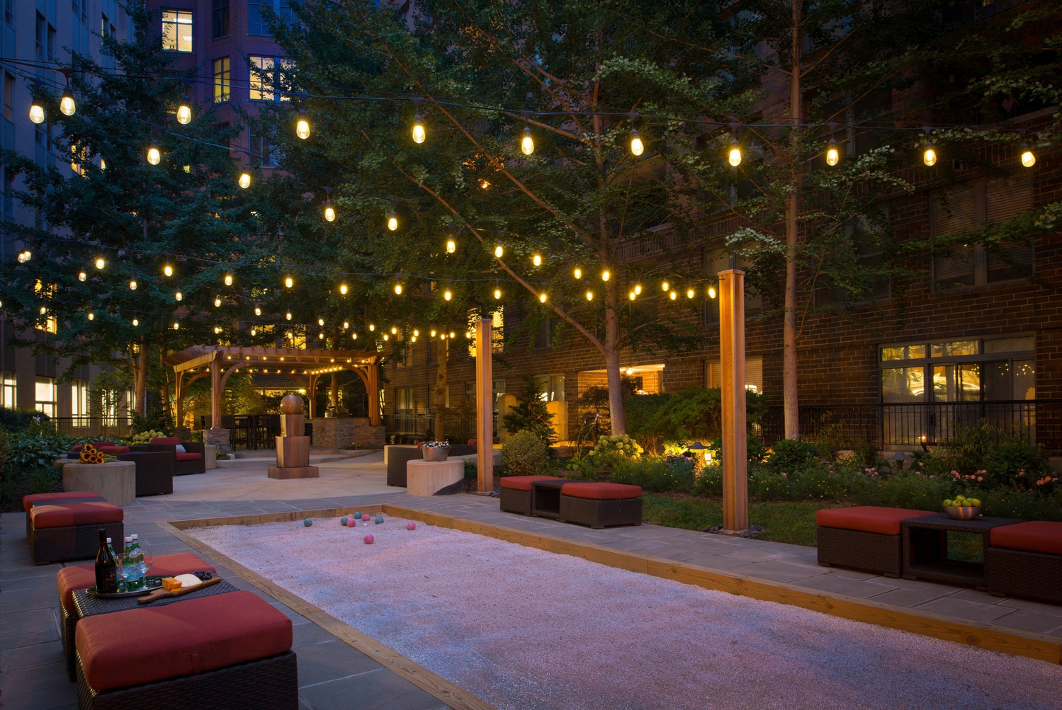 a courtyard with lights and a pool at night