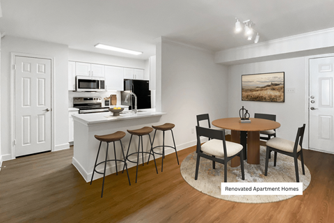 A kitchen with a bar and chairs in the middle of the room.