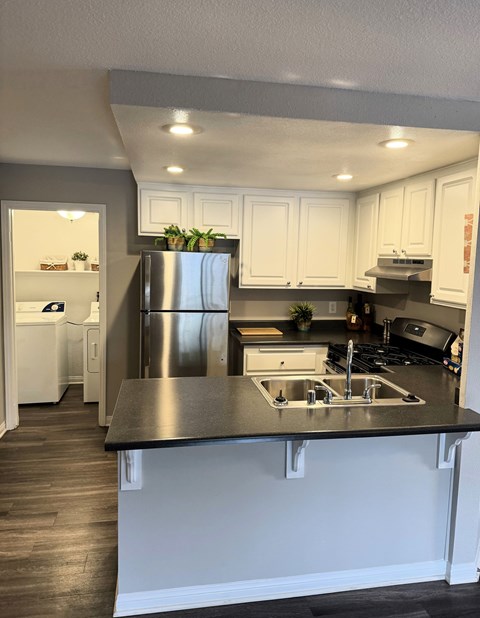 A kitchen with white cabinets and a black countertop.