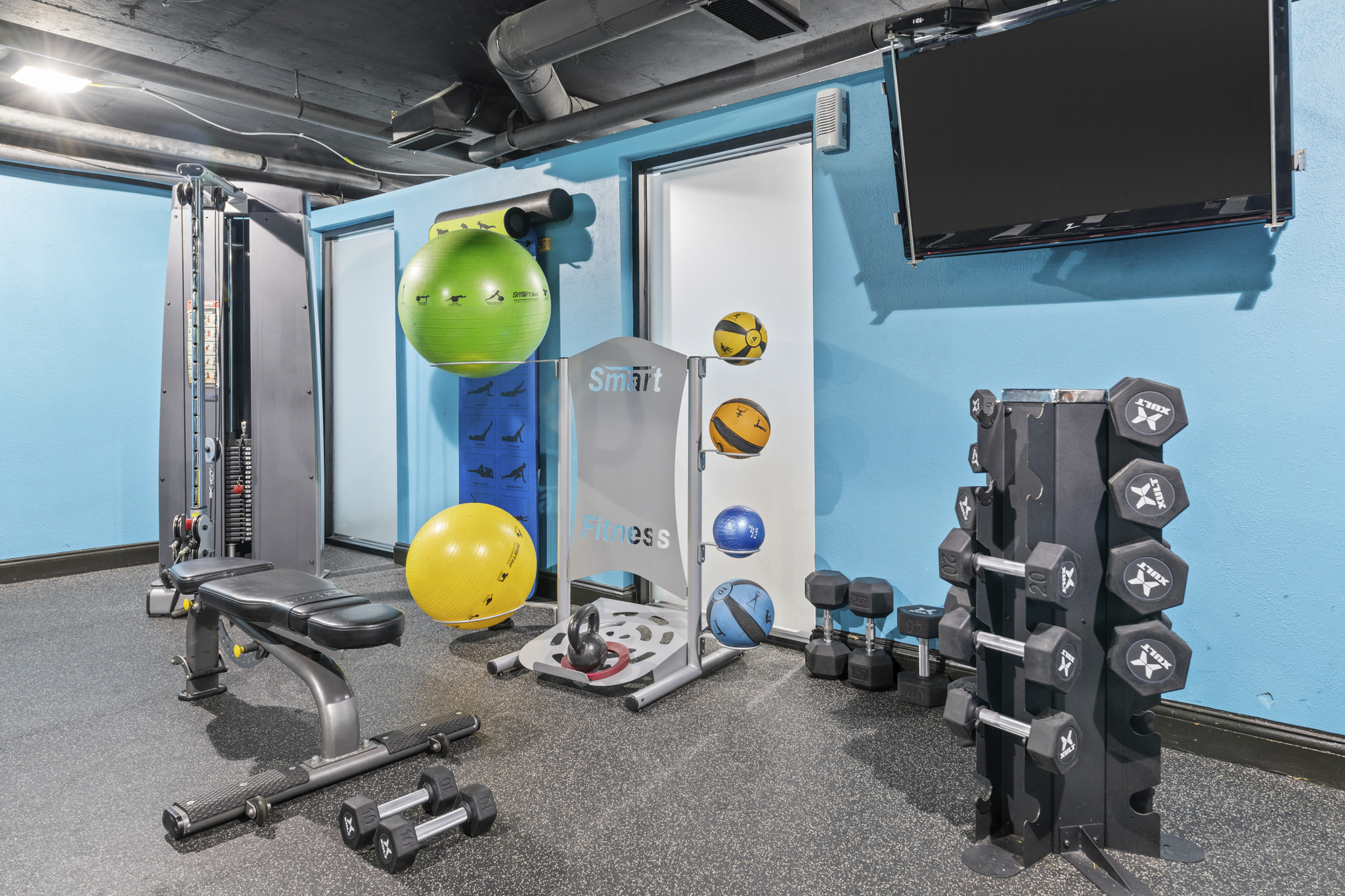 a workout room with weights and a yellow ball in the middle of it