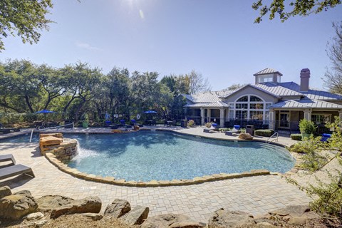 a large swimming pool with a house in the background