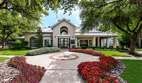 A white building with a red flower bed in front of it.