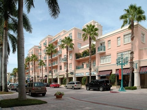 a large pink building on a street with cars and palm trees