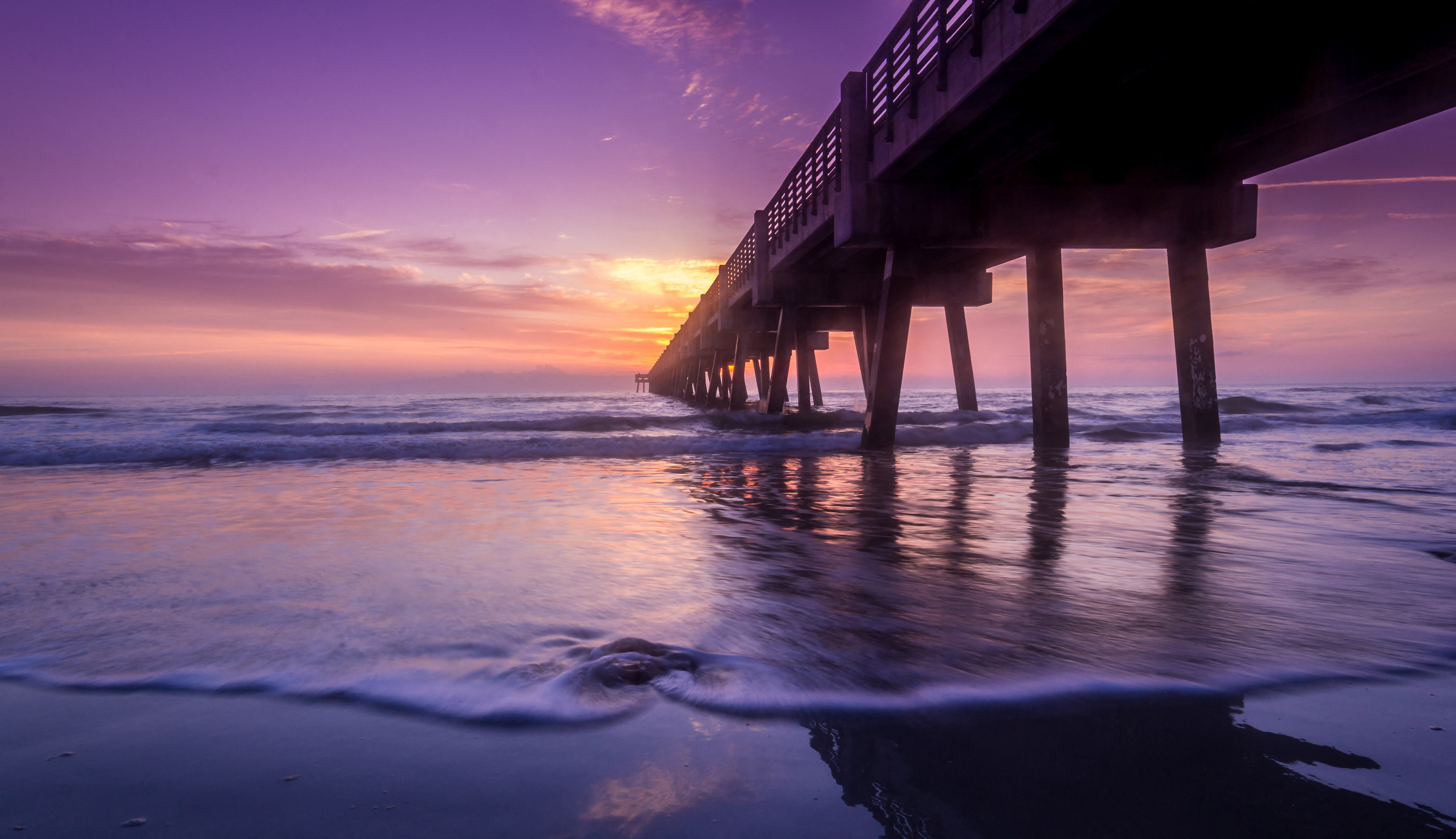 a pier on the beach at sunset