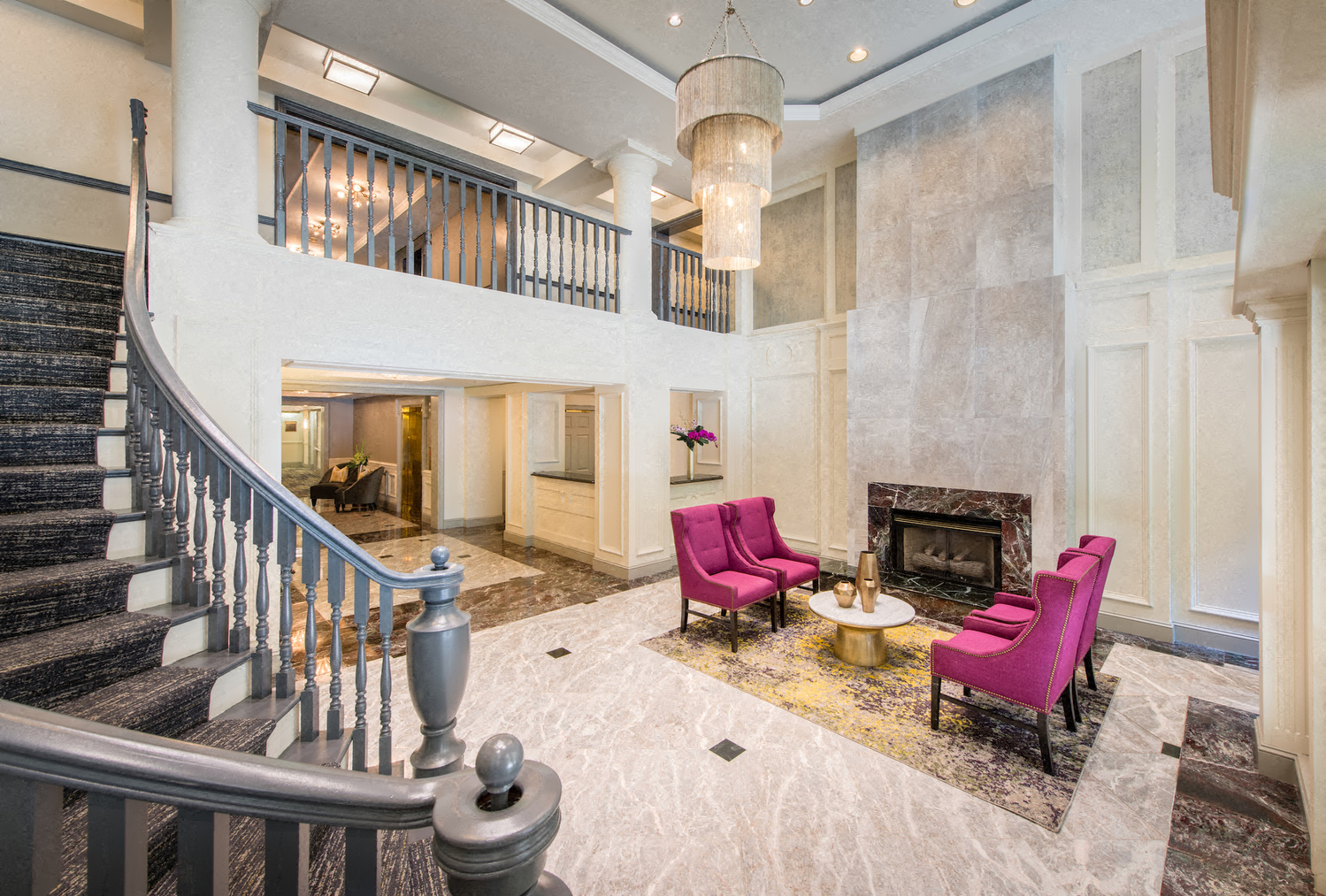 a lobby with a staircase and chairs and a fireplace