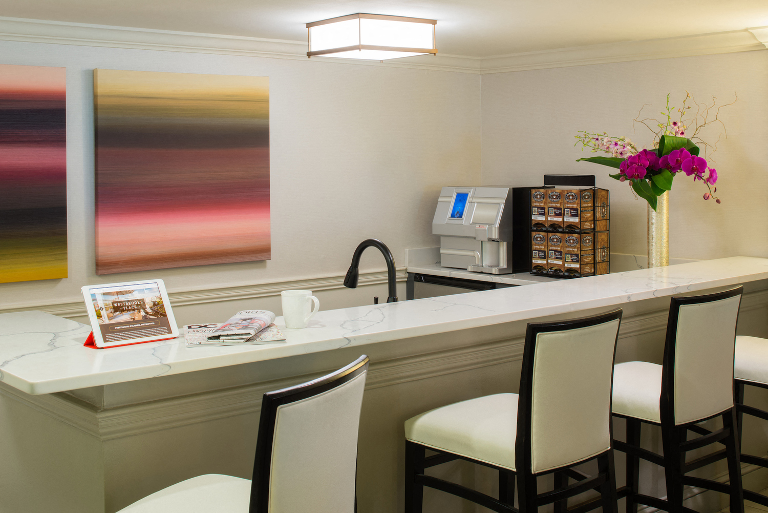 a counter with three chairs and a sink in a hotel room
