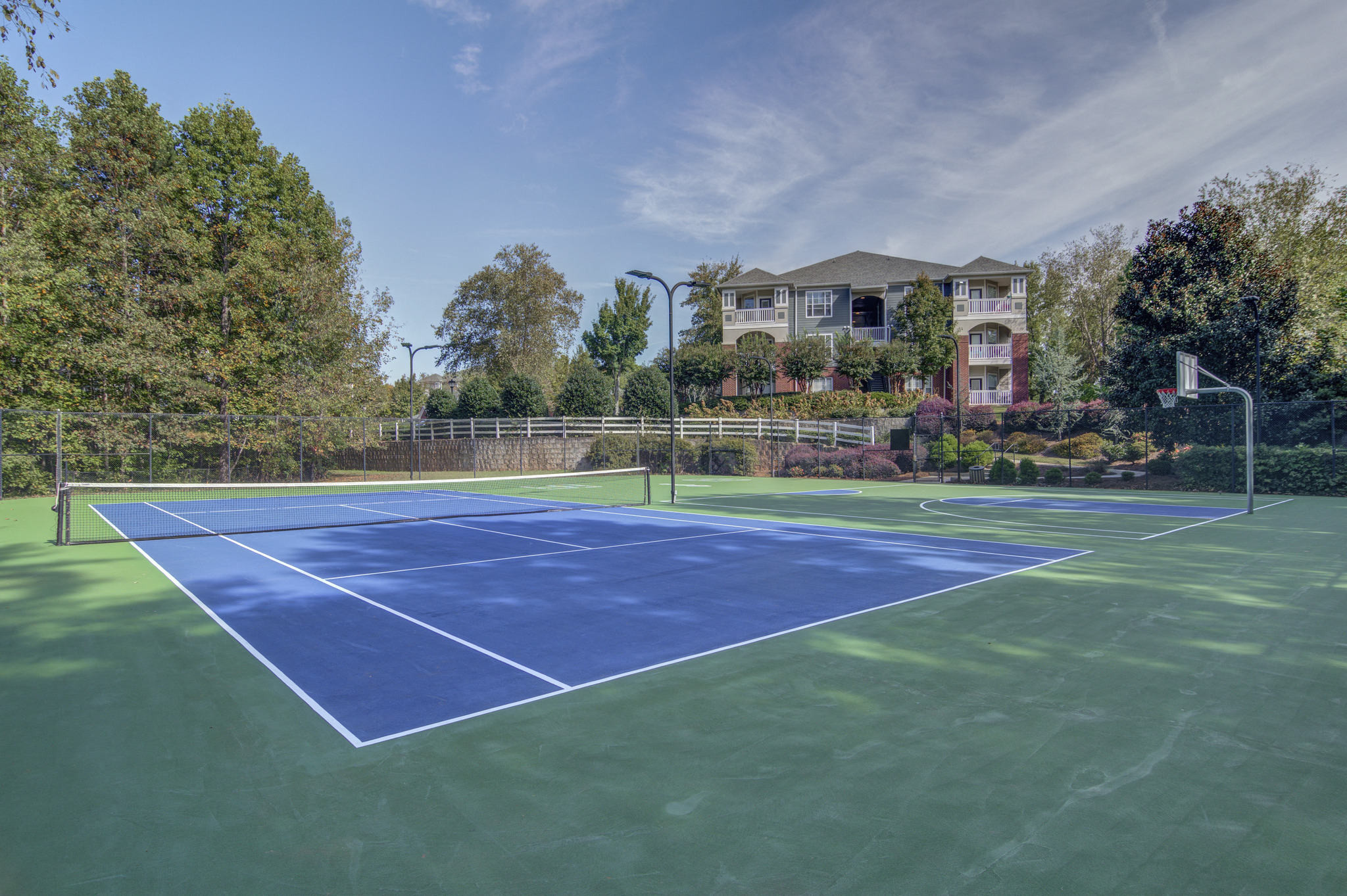 a blue and green tennis court with a house in the background