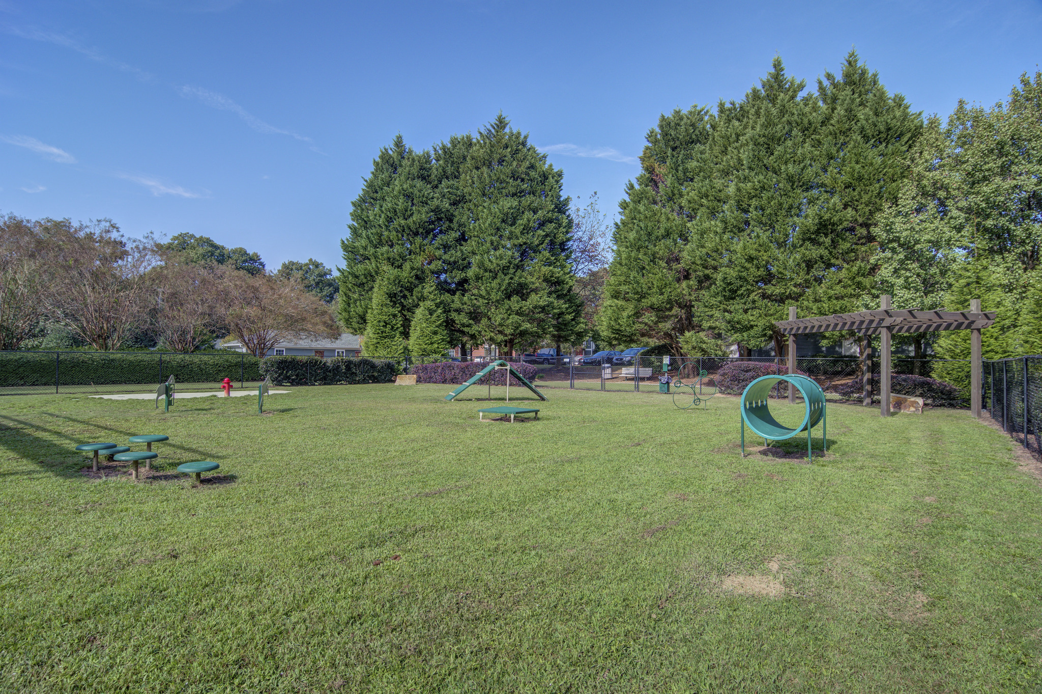a large grassy park with a playground and picnic tables