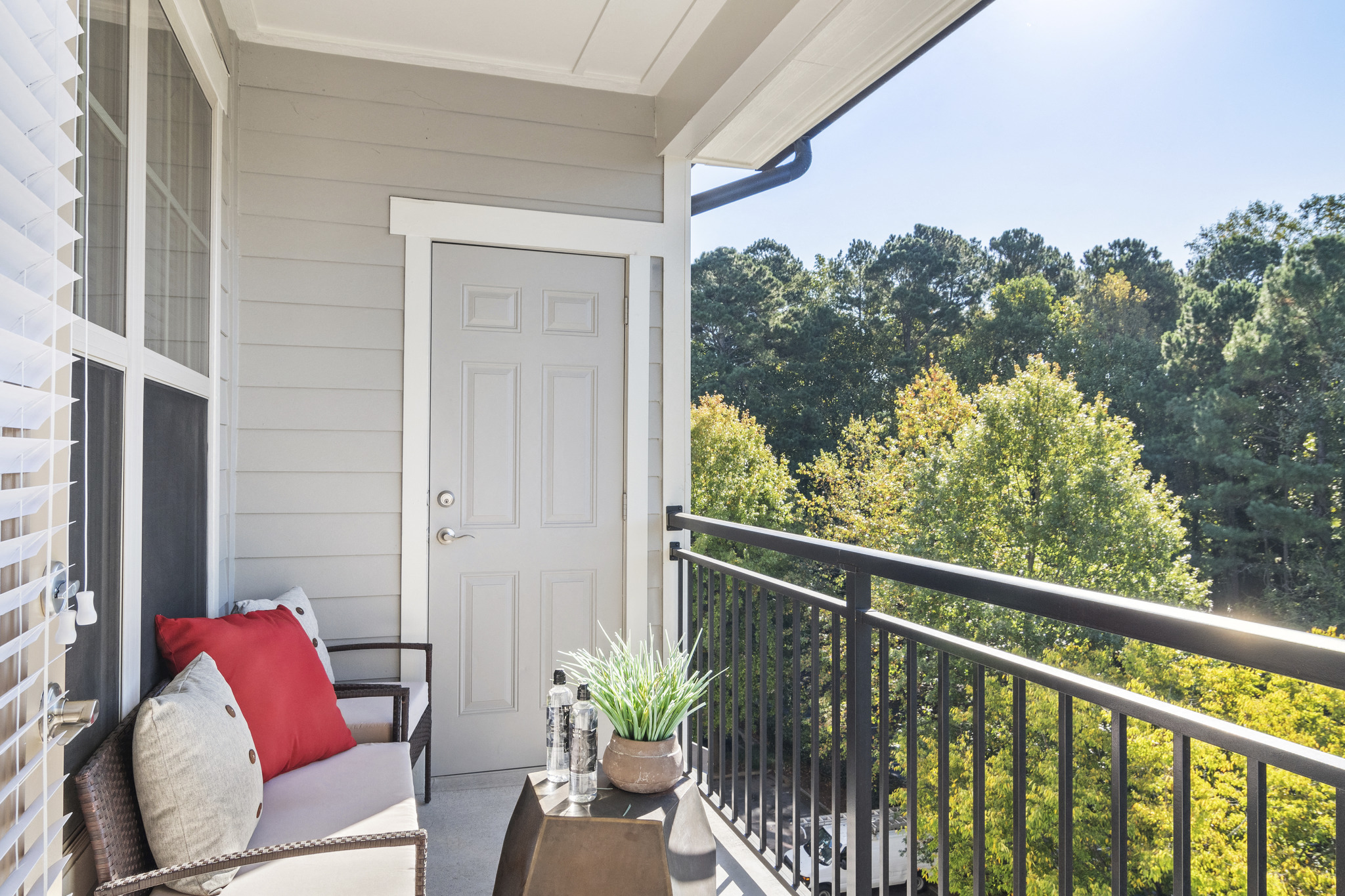 a porch with a white door and a balcony with a couch and a table